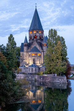 Temple Neuf, a Reformed church, Metz, Moselle, France. This Neo-Romanesque religious building, constructed of dark sandstone, stands on the waterfront and is illuminated at dusk.