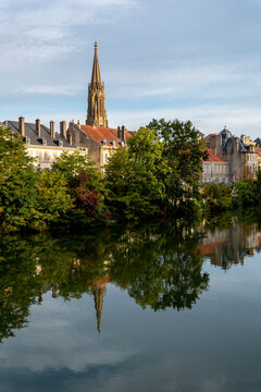 Temple Neuf, a Reformed church, Metz, Moselle, France. The building's spire rises above the trees and rooftops of the city, reflecting in the Moselle River