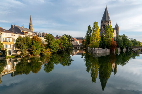 Temple Neuf, a Reformed church, Metz, Moselle, France. The Neo-Romanesque building, constructed of dark sandstone, and its trees in autumn colors are reflected in the Moselle River