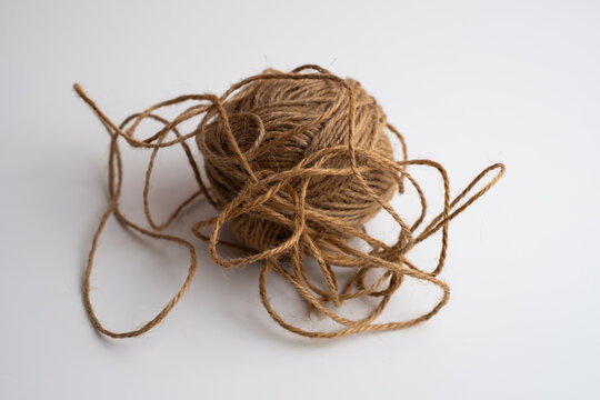 Tangled ball of brown jute twine with loose loops on white background, natural rope string for craft and packaging, copy space