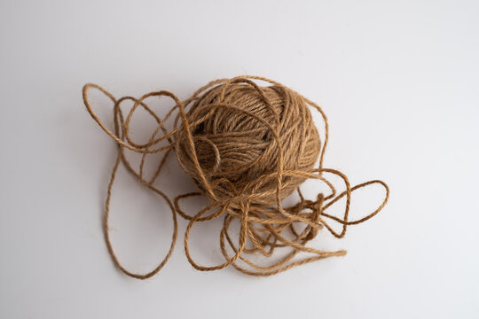 Tangled ball of brown jute twine with loose loops on white background, natural rope string for craft and packaging, copy space