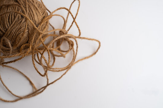 Tangled ball of brown jute twine with loose loops on white background, natural rope string for craft and packaging, copy space