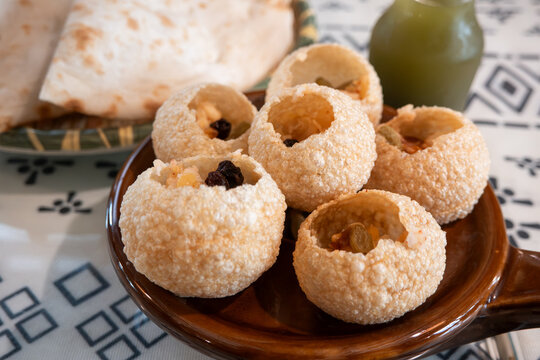 Traditional Indian panipuri golgappa snack served with mint flavored water.