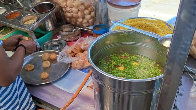 Street food vendor preparing and packing pani puri at stall