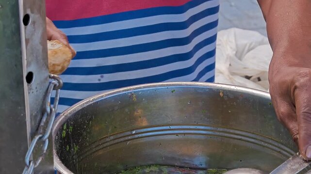 Street vendor filling spicy water into pani puri