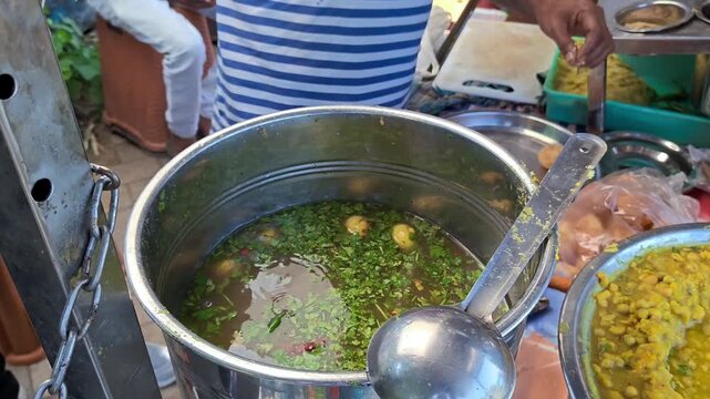 Street vendor filling spicy water into pani puri