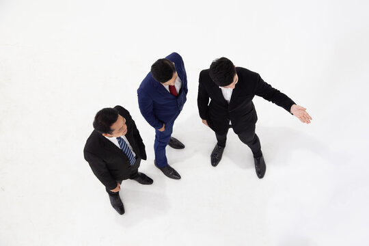 Top view of Asian business men in suits standing together on white background, pointing direction for corporate vision, strategic leadership, future partnership, and business guidance