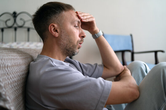AI job loss and unemployment leave worried man sitting on home floor facing financial insecurity and uncertain future as automation replaces workers.