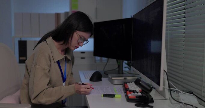 Woman machine learning researcher reviewing printed model results with highlighter at desk