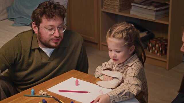 Caucasian child drawing on paper with colored pencils while Jewish parents look on. Clip fits family lifestyle ads and early childhood education marketing content