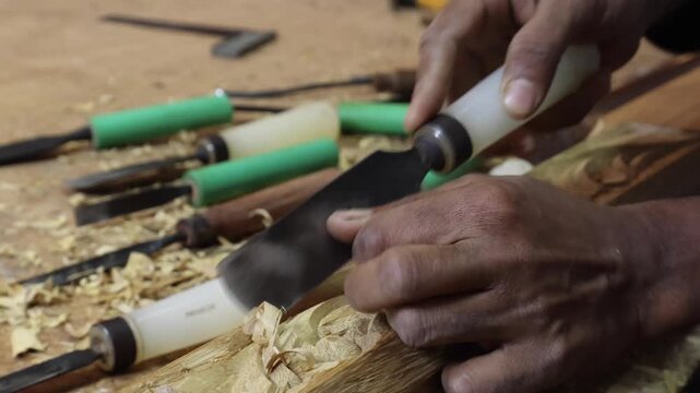 View of a craftsman using a chisel to carve wood in a traditional workshop in Sur, Ash Sharqiyah South G, Oman.
