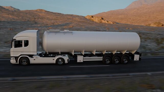 An aerial camera follows a white tanker truck approaching along a bend, then moves past the vehicle and tracks its departure through the rocky desert landscape.