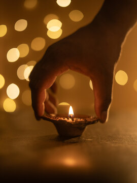 Keeping Traditional Clay Diya with a Lit Flame Against a Dreamy Warm Golden Bokeh Background, Festive Diwali Close-Up Shot
