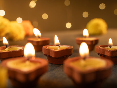 Traditional Clay Diya with a Lit Flame Against a Dreamy Warm Golden Bokeh Background, Festive Diwali Close-Up Shot
