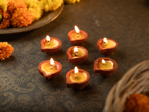 Traditional Clay Diya with a Lit Flame Against a Dreamy Warm Golden Bokeh Background, Festive Diwali Close-Up Shot
