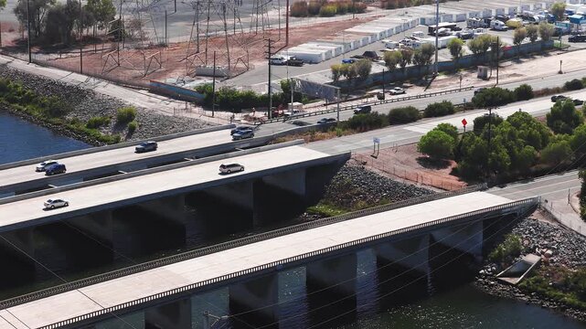 Aerial view of multiple concrete highway bridges spanning over a coastal river channel with passenger cars driving along roadways near Long Beach in sunny weather.