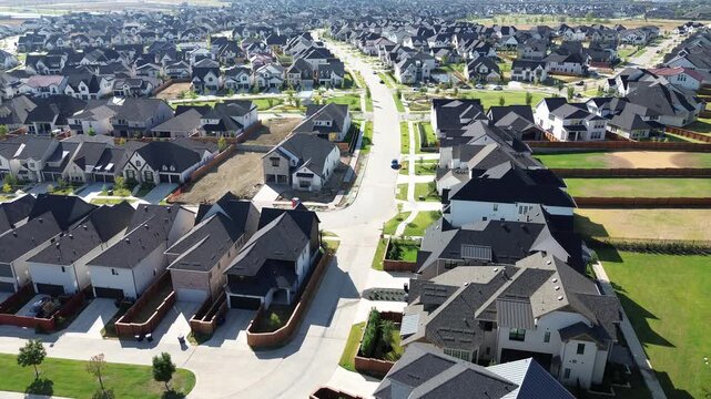 Expansive subdivision layout exhibits newly paved curved roadways modern suburban rooftops along Frisco. Earthmoving machines prepare adjoining vacant parcels under sunlight in, Texas