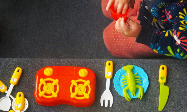 High-angle view of a little girl playing with plastic kitchen toys.