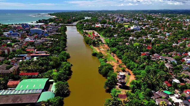 Aerial view of the Nilwala River flowing through the town of Matara, surrounded by lush tropical vegetation and residential buildings in Matara, Southern Province, Sri Lanka.
