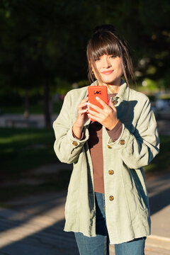 Young woman smiling and using smartphone outdoors