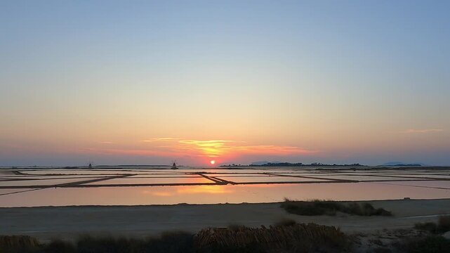 Golden sunset over tranquil salt pans near Trapani, Italy