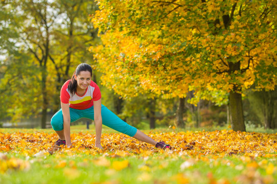 Woman Warming Up and Stretching in a Colorful Autumn Park
