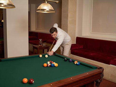 Young Man Aiming Cue Ball While Playing Billiards in Luxury Game Room