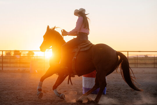 Horseback rider turning horse at sunset in outdoor arena