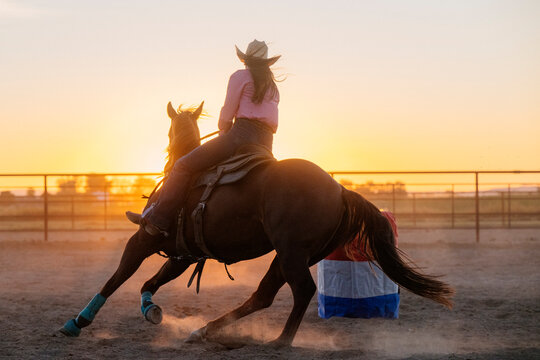 Horse rider making a sharp turn at sunset in outdoor riding arena