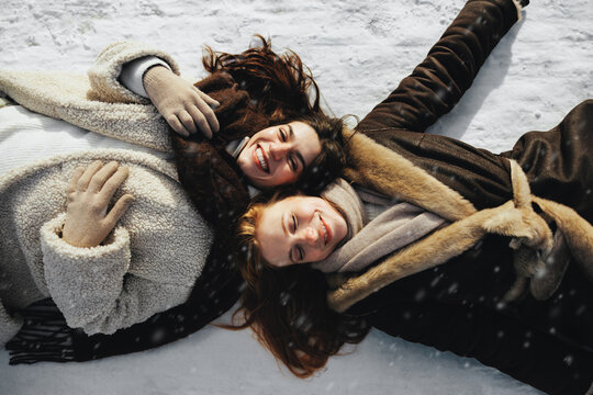 Friends smile together while lying in snow