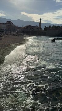 Sunlit Foamy Sea Waves Washing Over Dark Pebble Beach in Slow Motion