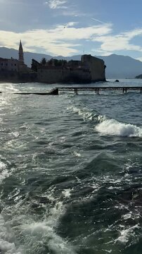 Foamy Sea Waves Rolling Near Coastal Pier and Historic Fortress Town