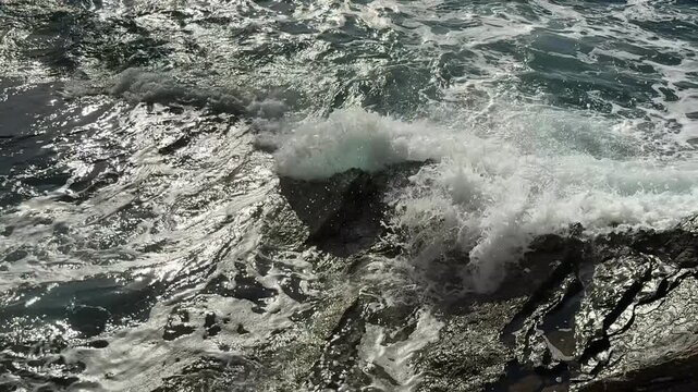Sparkling Sea Waves Surging on Wet Textured Coastal Rocks in Sun