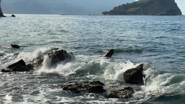 Sea Waves Splashing on Dark Foreground Rocks with Green Island
