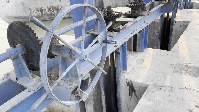 Manual crank wheel mechanism on rustic water sluice gate