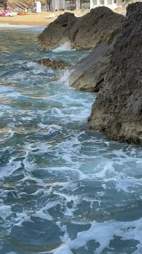 Vertical Shot of Foaming Turquoise Sea Water Swirling by Dark Rocks