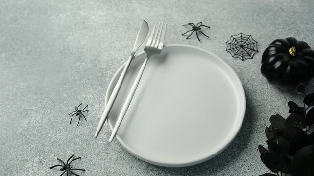 Halloween table setting with plate fork and knife decorated with spiders and pumpkin