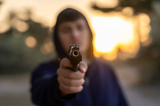 A man is pointing a gun barrel at the camera.