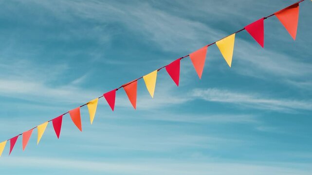 Colorful pennant flags strung across a bright blue sky with wispy clouds