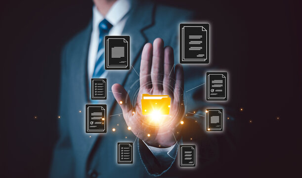 Businessman managing digital files through a virtual interface with a glowing folder and floating documents representing document management file organization workflow automation and technology.