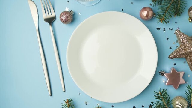 White plate with silverware and Christmas decorations on a blue background