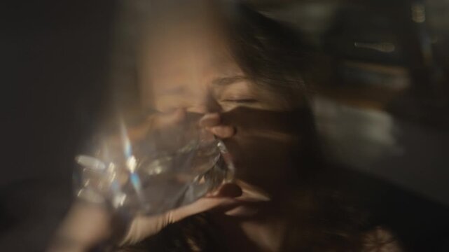 Caucasian young woman drinking water from bottle and pressing cold plastic against forehead in pain. Clip suitable for healthcare campaigns, dehydration warnings or hangover relief ads