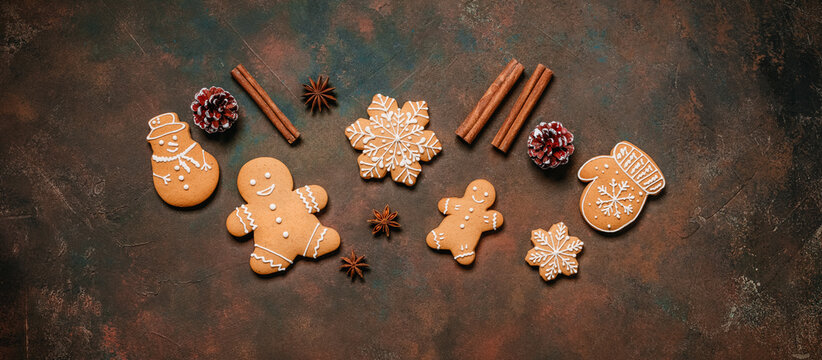 Christmas gingerbread cookies with spices and pine cones on a dark rustic background, top view, flat lay, banner