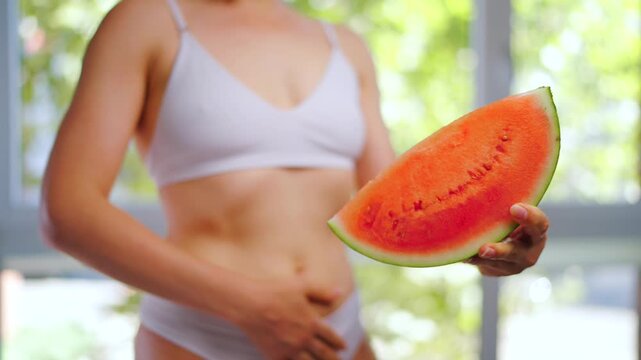 Woman is holding a piece of watermelon in her hand.