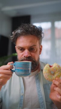 Sweet addiction concept. A man eats a donut and drinks coffee. 