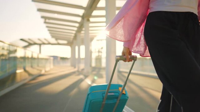 Woman confidently pulling a suitcase in an airport terminal.