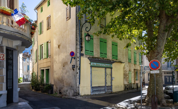Colorful french houses on the central square of Quillan (Aude, France) with traditonal window shutters and a plane tree
