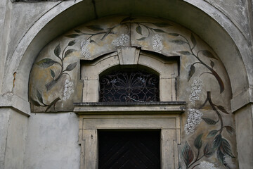 Ornate stone lintel and tympanum under a large arch with floral wall paintings at a Renaissance prince's castle. © Pol Badger