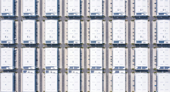  Aerial top view photo of identical white warehouses in grid pattern at industrial park
