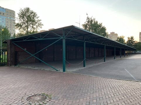 Long covered parking shelter with green metal frame in urban courtyard